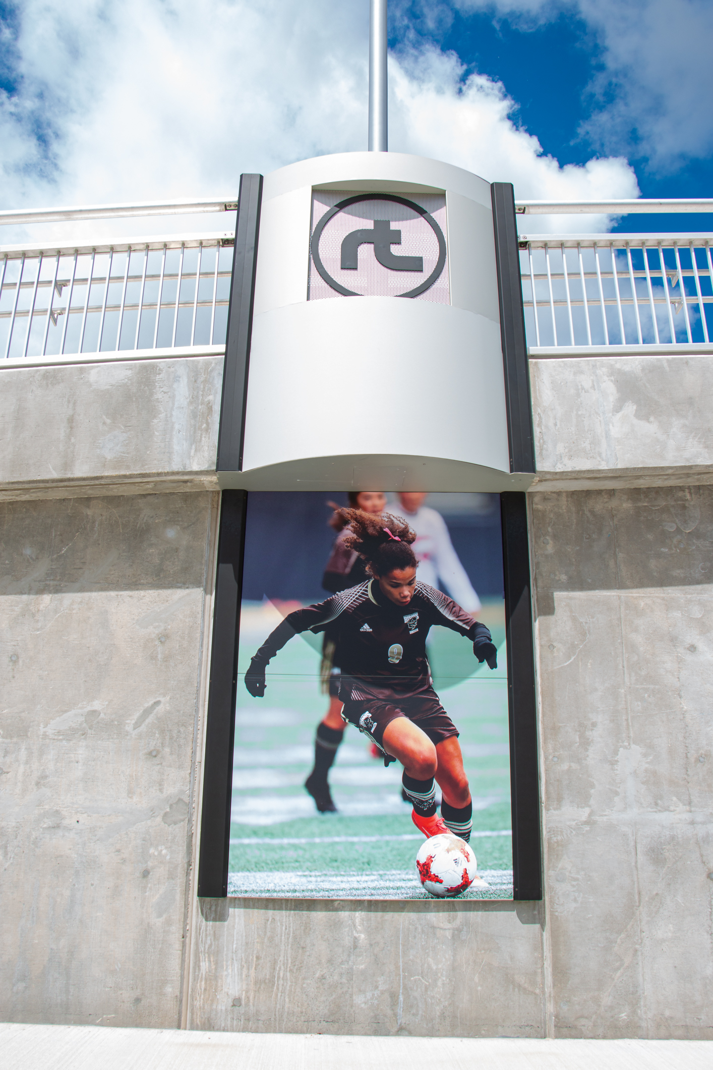 A woman playing soccer is displayed in an image on a concrete wall