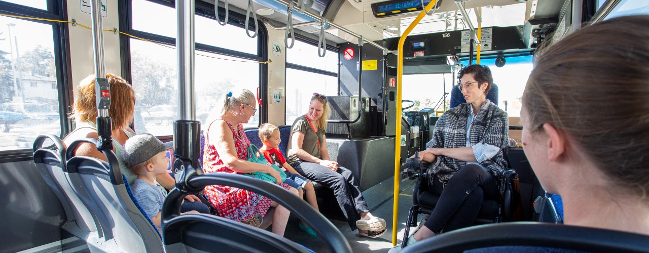 A group of Winnipeg Transit passengers, including parents with children and a wheelchair user